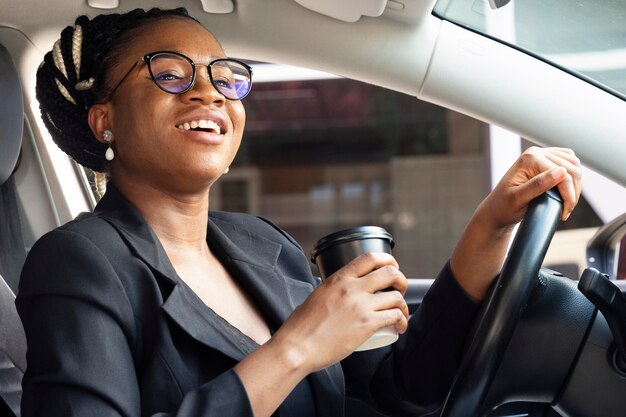 Vista laterale della donna che tiene la tazza di caffè mentre nella sua auto