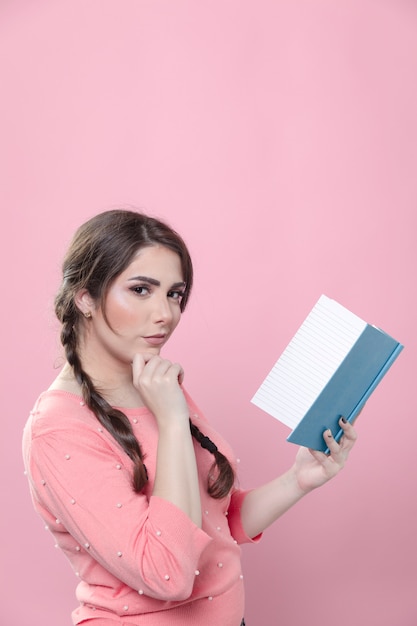 Vista laterale della donna che tiene un libro e che agisce astuto