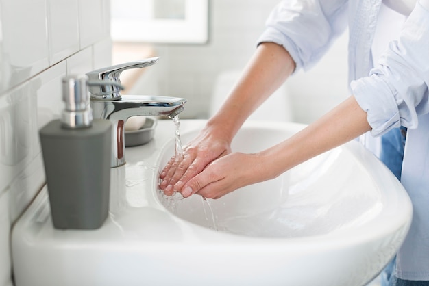 Vista laterale della donna che usando acqua per lavarsi le mani