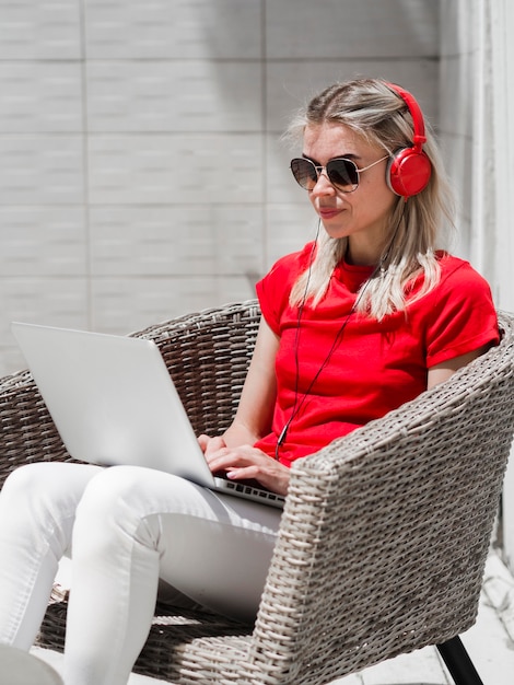 Vista laterale della donna con gli occhiali da sole che lavora al computer portatile all'aperto