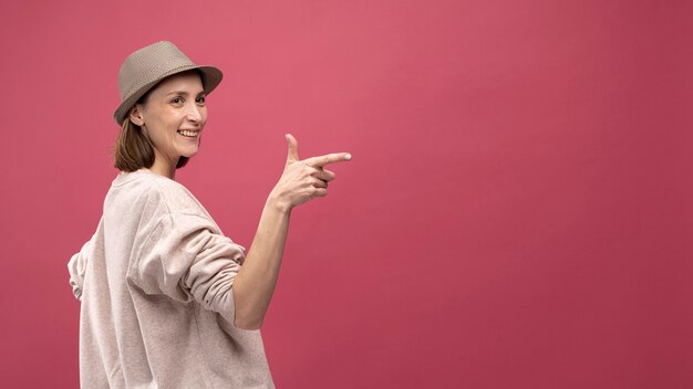 Vista laterale della donna con il cappello che posa e che indica