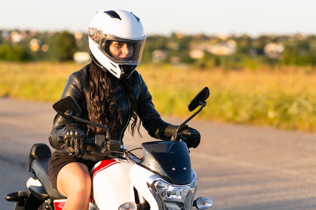 Vista laterale della donna con il casco in sella a una moto