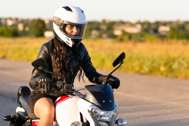 Vista laterale della donna con il casco in sella a una moto