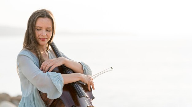 Vista laterale della donna con violoncello e copia spazio