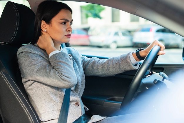 Vista laterale della donna di affari che ha dolore al collo in macchina