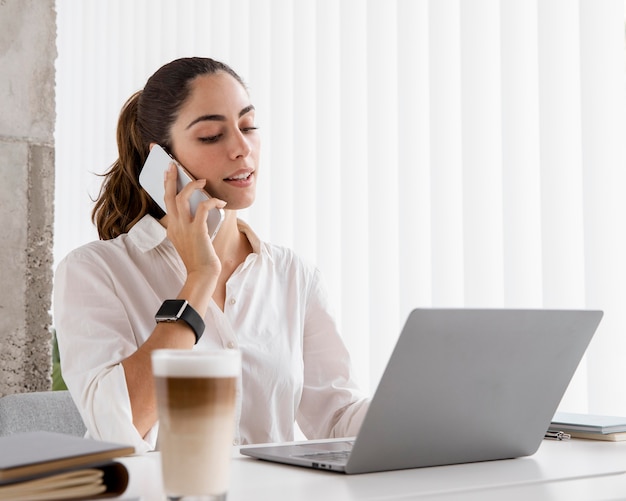 Vista laterale della donna di affari che lavora con smartphone e laptop