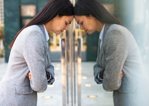 Vista laterale della donna di affari che si appoggia la sua testa contro la porta di vetro