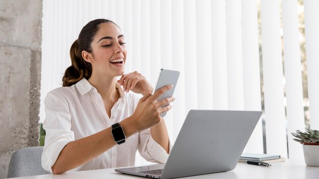 Vista laterale della donna di affari con smartphone e laptop