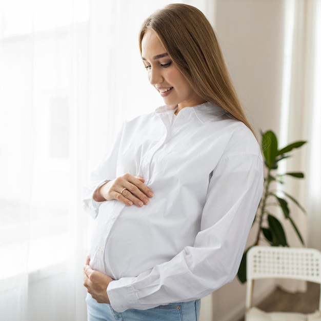 Vista laterale della donna di affari incinta che tiene la sua pancia