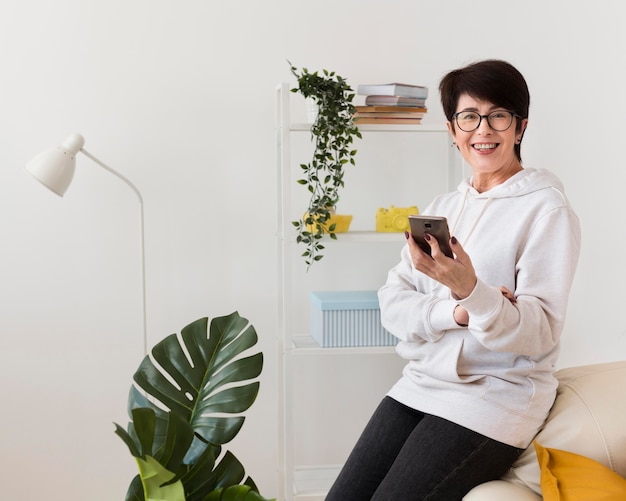 Vista laterale della donna di smiley con lo smartphone