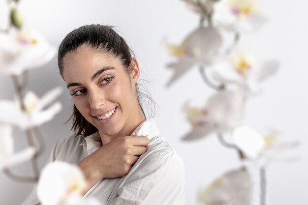 Vista laterale della donna di smiley con orchidee sfocati