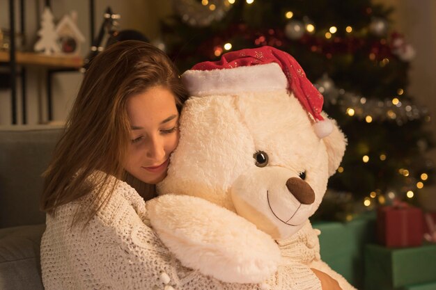 Vista laterale della donna donna sul Natale che abbraccia il suo orsacchiotto