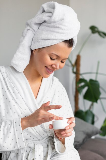 Vista laterale della donna in accappatoio e asciugamano con crema