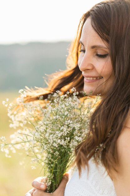 Vista laterale della donna in natura con il mazzo di fiori
