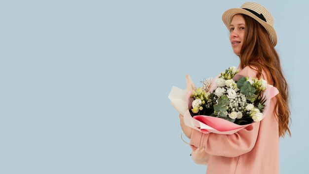 Vista laterale della donna in posa con bouquet di fiori primaverili e copia spazio