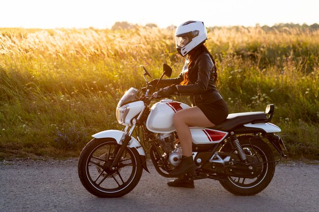 Vista laterale della donna in sella a una moto con il casco