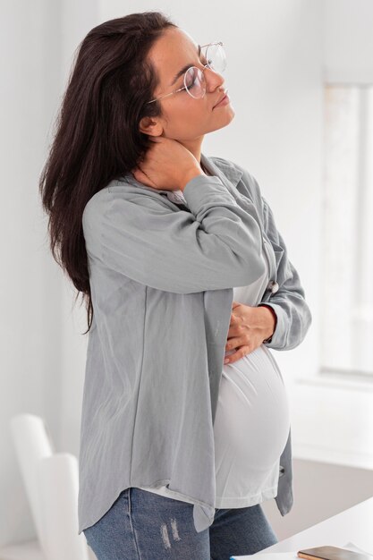 Vista laterale della donna incinta che tiene il suo collo