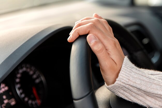 Vista laterale della donna nella sua auto tenendo il volante durante la guida