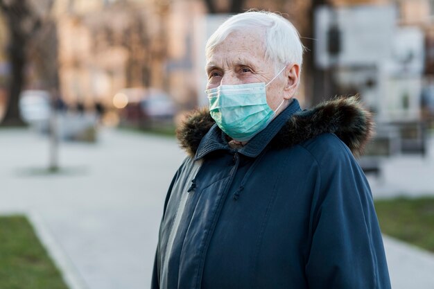 Vista laterale della donna più anziana con la mascherina medica nella città