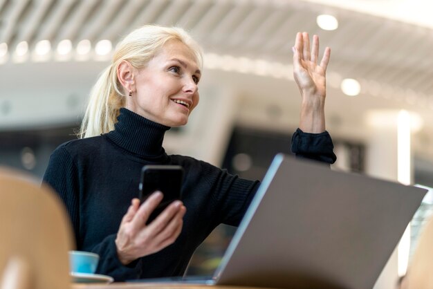 Vista laterale della donna più anziana di affari che ordina qualcosa mentre si lavora al computer portatile