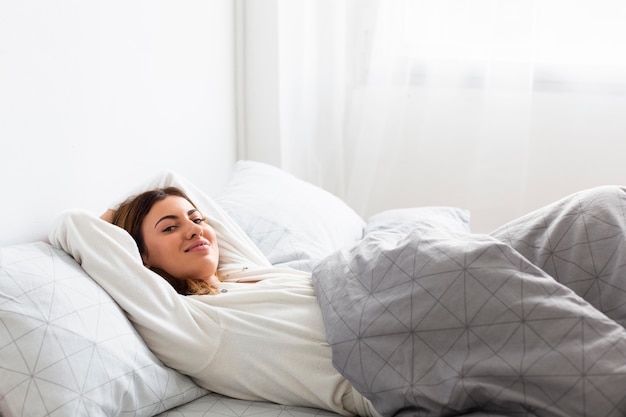 Vista laterale della donna rilassata a letto in pigiama