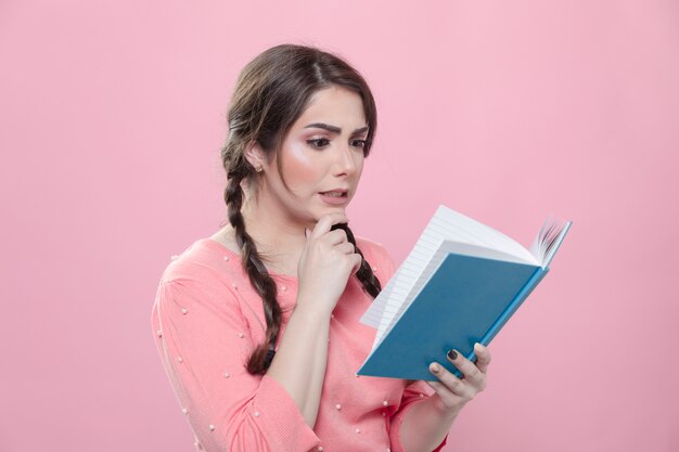 Vista laterale della donna scioccata da ciò che sta leggendo nel libro che sta tenendo