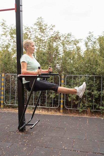 Vista laterale della donna senior che lavora fuori all'aperto