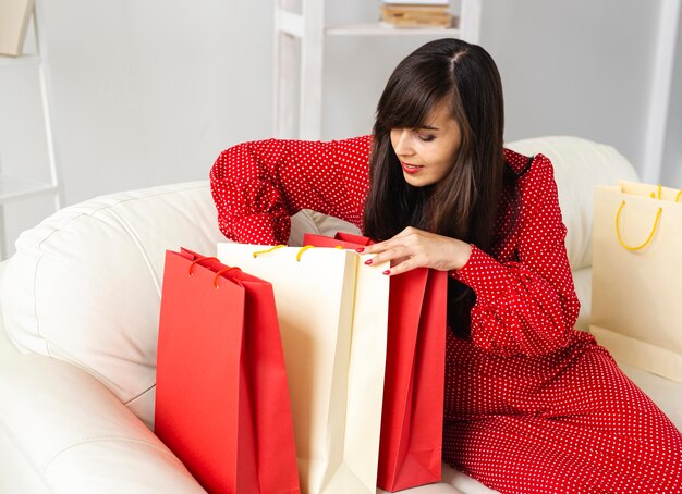 Vista laterale della donna sorridente che controlla gli elementi che ha ricevuto durante lo shopping di vendita