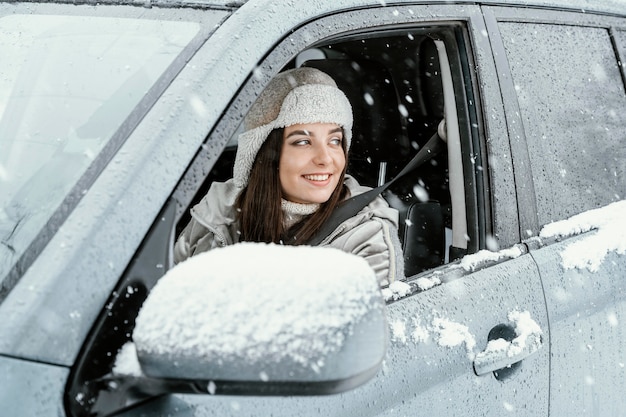 Vista laterale della donna sorridente che guida l'auto per un viaggio su strada