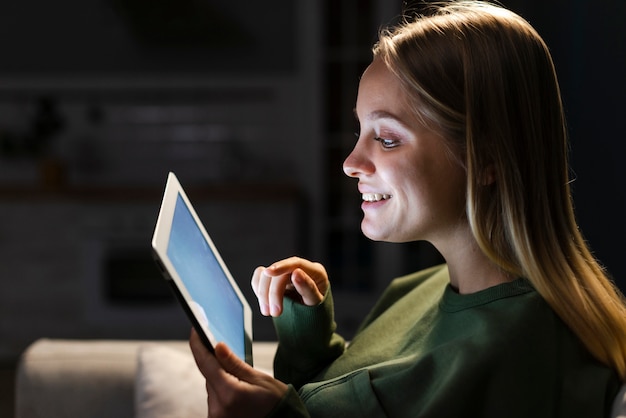 Vista laterale della donna sorridente con il tablet