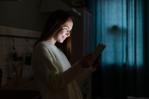 Vista laterale della donna sorridente con il tablet