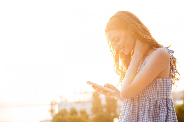 Vista laterale della donna sorridente graziosa dello zenzero in vestito