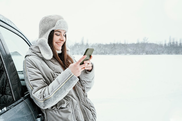 Vista laterale della donna sorridente utilizza lo smartphone durante un viaggio con lo spazio della copia