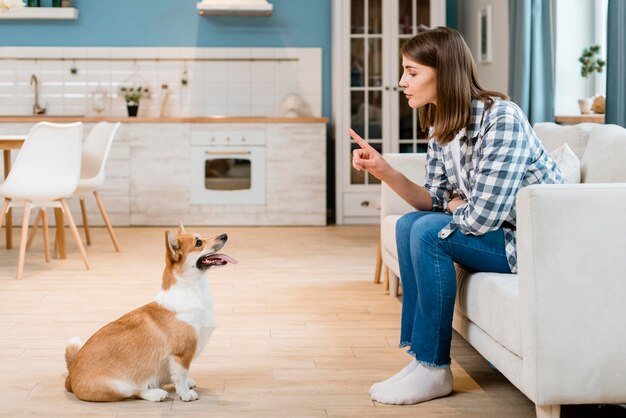 Vista laterale della donna sul divano addestrando il suo cane