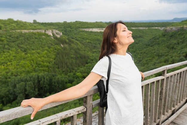 Vista laterale della donna sul ponte che gode della natura