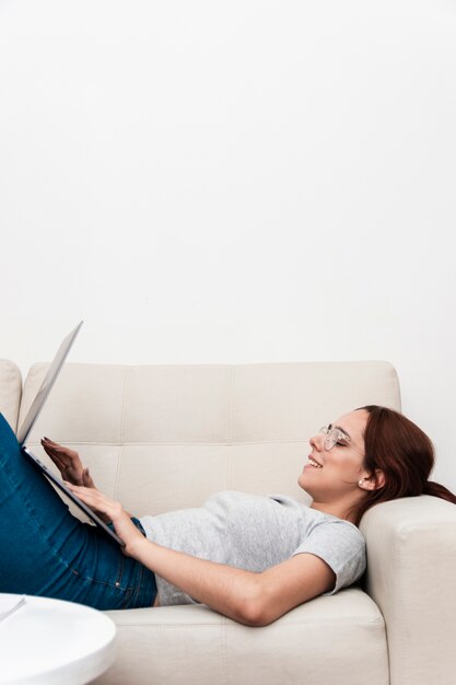 Vista laterale della donna sullo strato che lavora al computer portatile