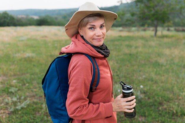 Vista laterale della donna turistica anziano con thermos