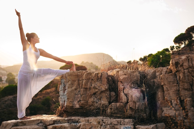 Vista laterale della giovane donna facendo yoga in natura