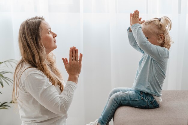 Vista laterale della madre che prega con il suo bambino