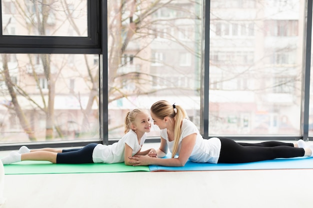 Vista laterale della madre e del bambino sulla stuoia di yoga a casa