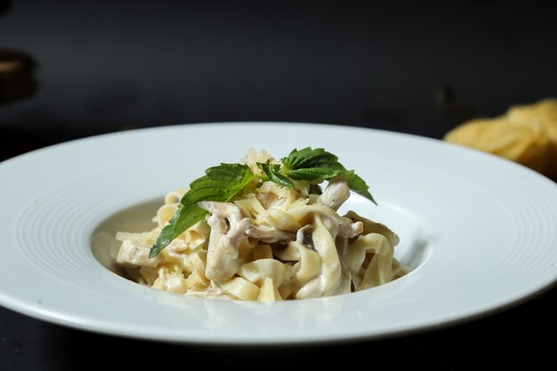 Vista laterale della menta della salsa crema dei funghi del formaggio del pollo del fettuccine della pasta