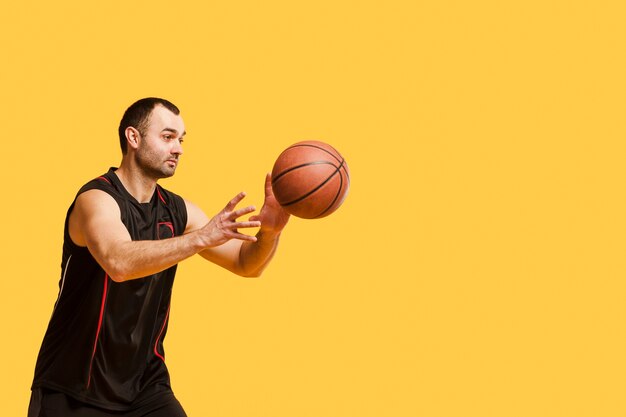 Vista laterale della pallacanestro di lancio del giocatore maschio con lo spazio della copia