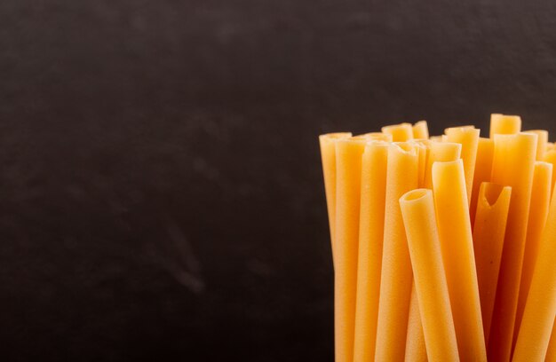 Vista laterale della pasta di bucatini su fondo nero con lo spazio della copia