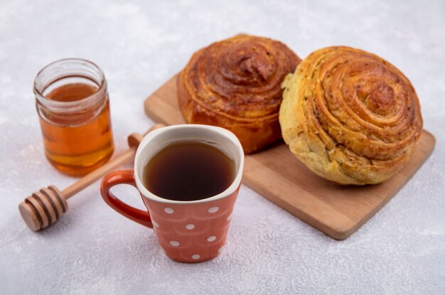 Vista laterale della pasticceria tradizionale azera gogal su una tavola da cucina in legno con una tazza di tè e miele su un vasetto di vetro su sfondo bianco