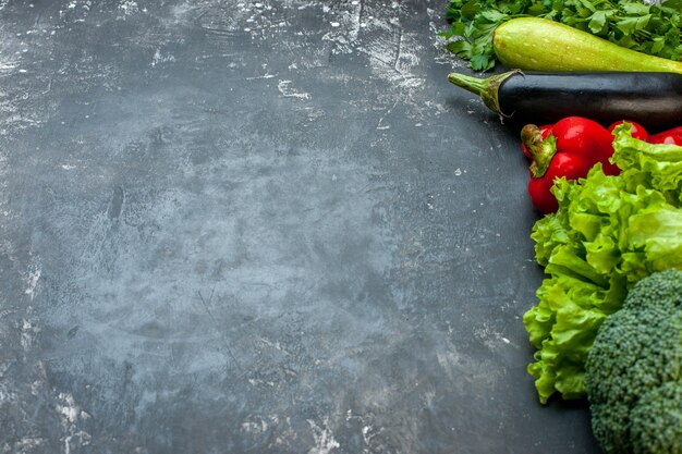 Vista laterale della preparazione della cena con verdure fresche e verde sul lato sinistro su sfondo scuro