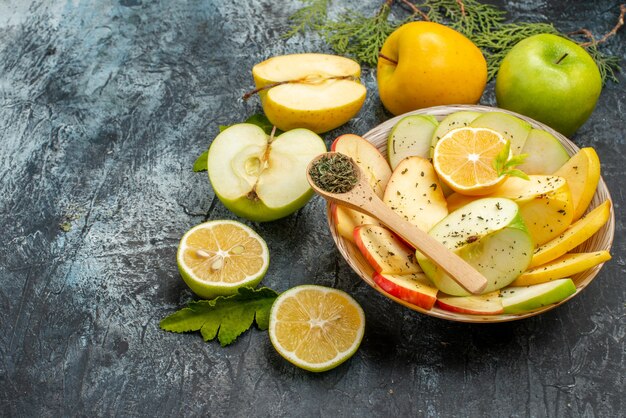 Vista laterale della raccolta di frutta organica naturale fresca su un piatto bianco posate lime cannella sul lato sinistro su uno sfondo scuro