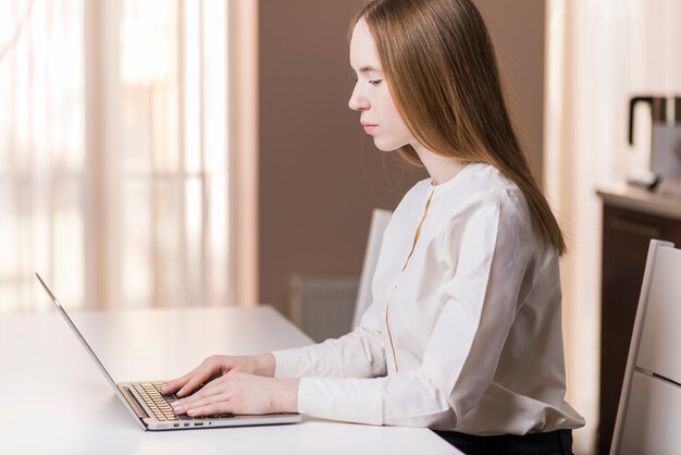 Vista laterale della ragazza che studia con il suo computer portatile