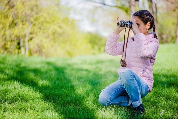 Vista laterale della ragazza concentrata con il binocolo