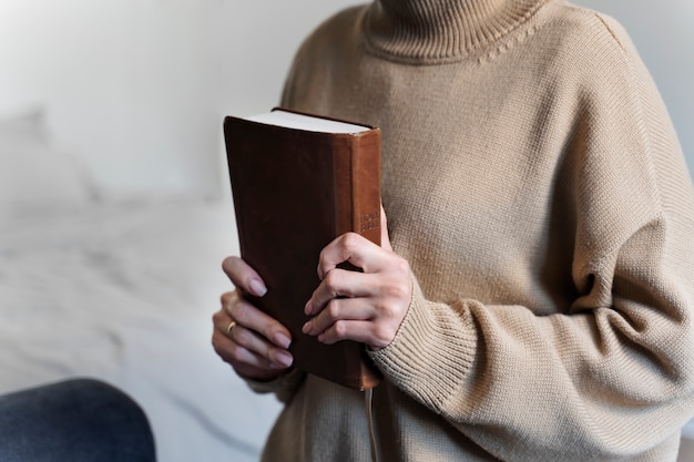 Vista laterale della Sacra Bibbia della holding della donna