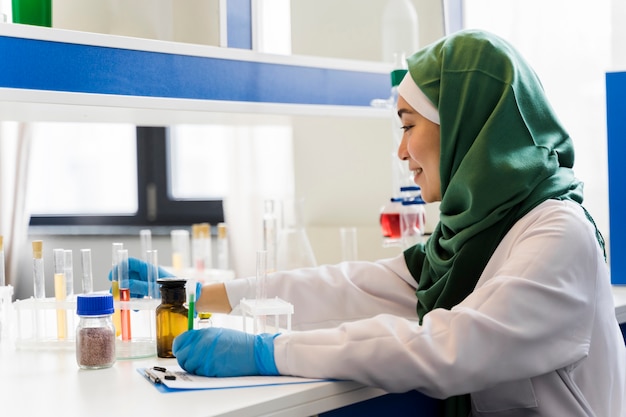 Vista laterale della scienziata con hijab e guanti chirurgici